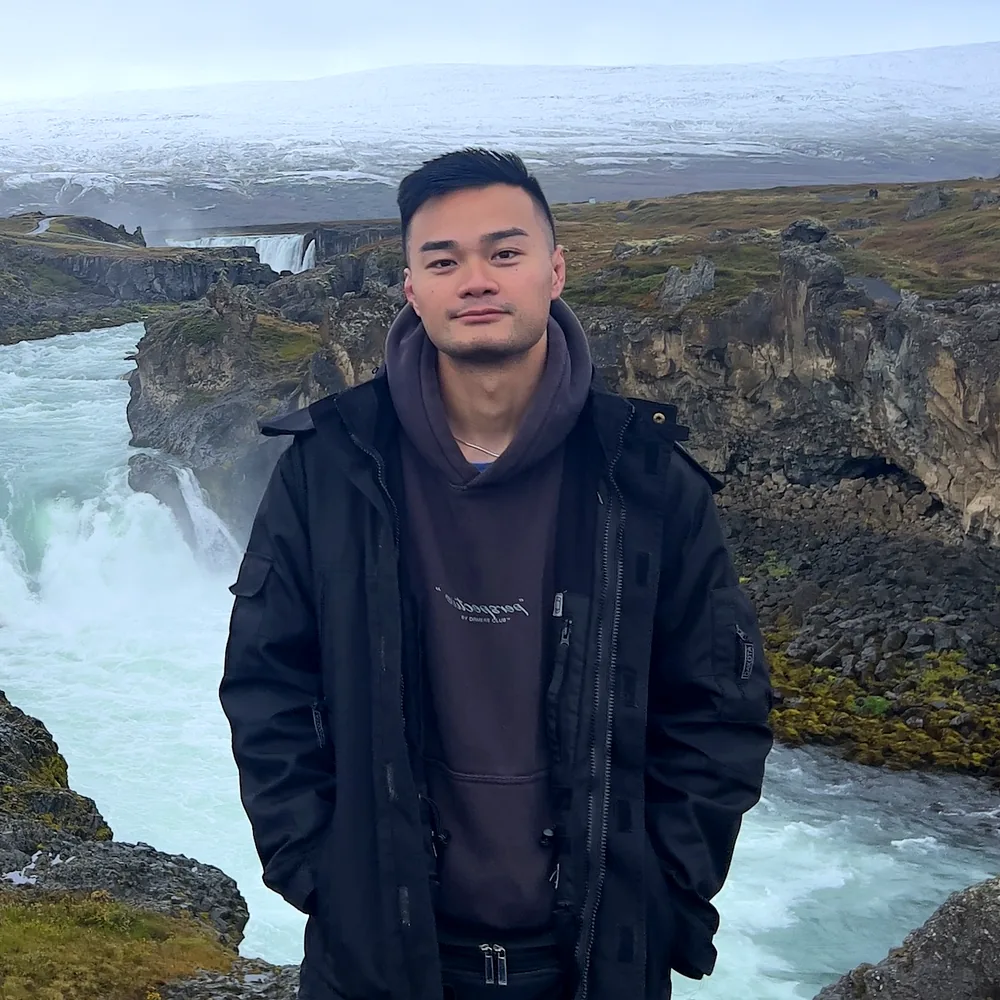 Thomas Le, RMT, standing outdoors by a river